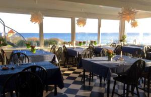 un restaurante con mesas y sillas azules y el océano en Badehotel Harmonien en Ærøskøbing