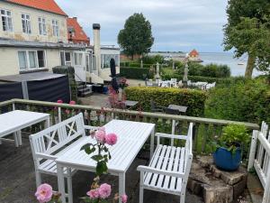 een witte tafel en stoelen op een balkon met bloemen bij Badehotel Harmonien in Ærøskøbing