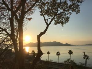 a sunset over the water with trees in the foreground at Sunset Village - Vacation STAY 15318v in Onomichi