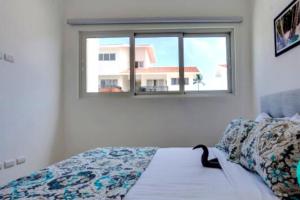 ein Schlafzimmer mit einem Bett und ein Fenster mit einer Katze drauf in der Unterkunft BAVARO PUNTA CANA Apartamento con Piscina in Punta Cana