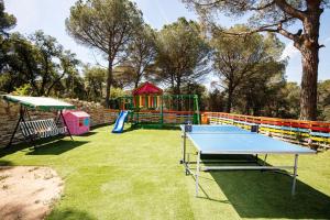 un tavolo da ping pong e un parco giochi in un cortile di Maravillosa casa con piscina grande y bosque a Tordera