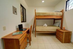 een slaapkamer met een bureau en een stapelbed bij Sámara Tarantela Houses, Casa Bambú in Sámara