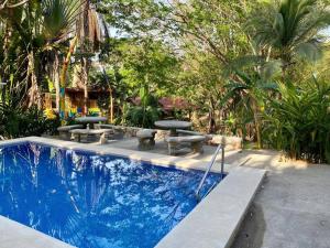 a swimming pool with picnic tables and benches in a yard at Sámara Tarantela Houses, Casa Bambú in Sámara