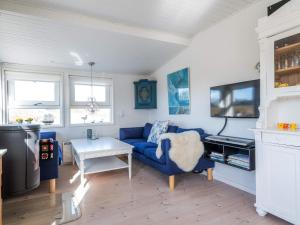 Una sala de estar con un sofá azul y un televisor. en 4 person holiday home in Fanø-By Traum, en Fanø