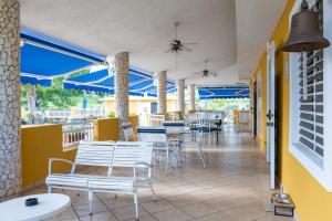 um restaurante com cadeiras e mesas brancas e guarda-sóis azuis em Casamares Private Room Arena with Pool and Jacuzzi 5 min to Boqueron and Beaches em Cabo Rojo