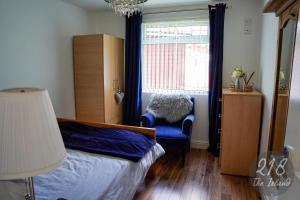 a bedroom with a bed and a chair and a window at The Cabin, Glan Gwna in Caernarfon