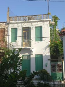 a white house with green doors and a balcony at Villa Elli 