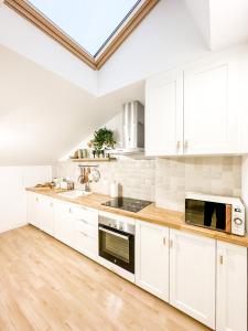 a kitchen with white cabinets and a wooden floor at El Olivo by ALÔGA in Corcubión +9 photos