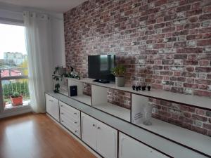 uma sala de estar com uma parede de tijolos e uma televisão em Apartament Fileo em Koszalin