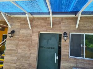 a front door of a building with a blue roof at Casa a 10 passos do mar - Temporada na Praia in Tamoios