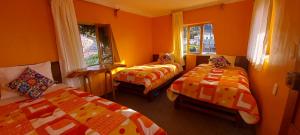 Duas camas num quarto com paredes e janelas cor-de-laranja em Musiña Lodge em Ocosuyo