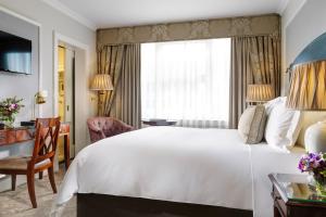 um quarto de hotel com uma grande cama branca e uma secretária em The Shelbourne, Autograph Collection em Dublin