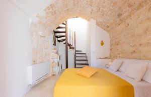 a bedroom with a yellow bed in a stone wall at Le Casette in Gravina Luxury in Villa Castelli