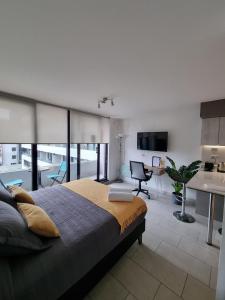 a bedroom with a large bed and a living room at Apartamentos Bauerle Curitiba in Temuco