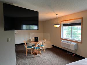 a room with a table and chairs and a television at GrandStay Hotel and Suite Waseca in Waseca