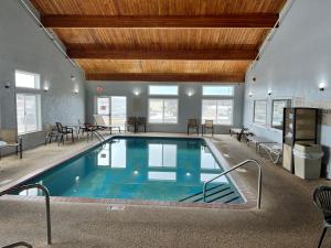 une grande piscine intérieure avec des chaises et une table dans l'établissement GrandStay Hotel and Suite Waseca, à Waseca