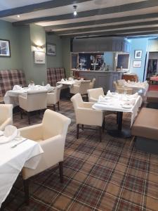 a dining room with white tables and white chairs at Schooner Hotel in Alnmouth