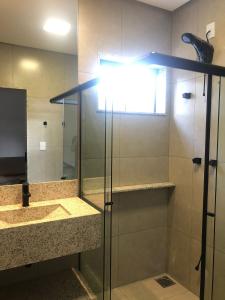 a bathroom with a shower and a sink and a mirror at ESCARPAS FLATS in Capitólio