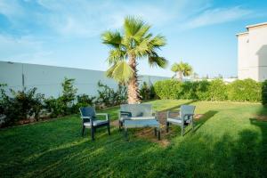 Villa 10 Palmeraie Golf Agadir في أغادير: ثلاثة كراسي وطاولة أمام نخلة