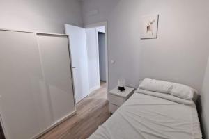 Loft en Madrid junto al metro. في مدريد: غرفة نوم بيضاء مع سرير ومرآة