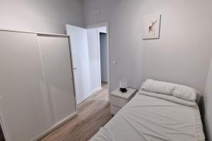 a white bedroom with a bed and a mirror at Loft en Madrid junto al metro. in Madrid
