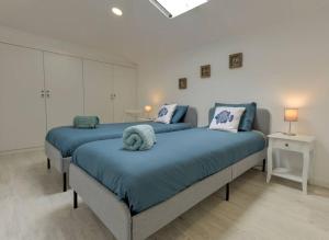 2 camas en un dormitorio con sábanas y almohadas azules en Sesimbra Loft, en Sesimbra