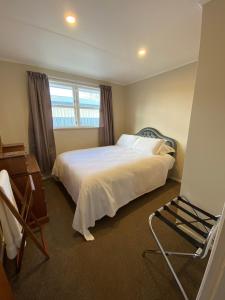 a bedroom with a bed and a chair and a window at Birch Court - Harakeke in Whanganui