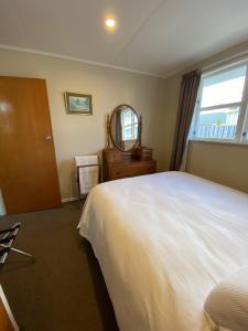 a bedroom with a large white bed and a mirror at Birch Court - Harakeke in Whanganui