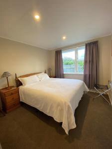 Un dormitorio con una gran cama blanca y una ventana en Birch Court - Harakeke en Whanganui