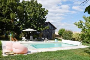 a swimming pool with pink chairs and an umbrella at Les bergeronnettes - Chambres d'Hôtes Bergerac in Bergerac