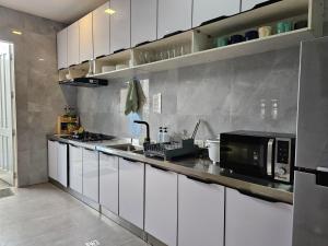 a kitchen with white cabinets and a black microwave at Spacious 5-bedroom, 4-bath townhouse in Legazpi City in Legazpi