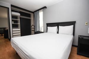 Un dormitorio con una gran cama blanca y una ventana en Tempo Rent Apart Hotel, en Santiago