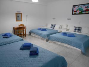 a room with three beds with blue sheets and a television at Studios Apartments Kapetanios in Perissa +109 photos