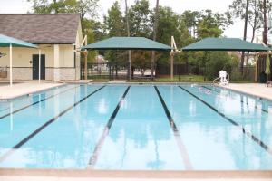 a swimming pool with blue water and umbrellas at Everything under 5 min. The Woodlands TX. Fully Equipped for Long stays as well. in Shenandoah