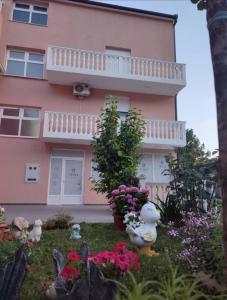 różowy dom z kwiatami przed nim w obiekcie Apartmani Hani w mieście Trebinje