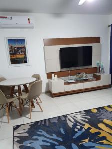 uma sala de estar com uma televisão e uma mesa e cadeiras em Casa Duplex Aconchegante de Frente para o Mar em Porto Seguro