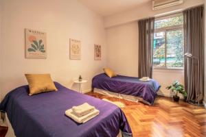 1 dormitorio con 2 camas con sábanas moradas y ventana en Fliphaus Junin 1600 - 2 Bd Recoleta Mall en Buenos Aires