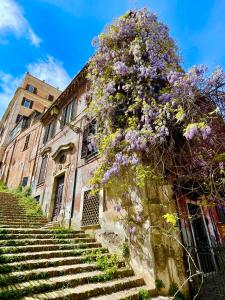 an old building with a tree with purple flowers at Sant’Onofrio - Trastevere Vatican apartment Roma in Rome