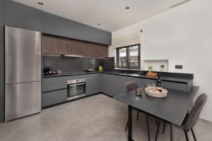 a kitchen with a table and a stainless steel refrigerator at 30 Senses Luxury Apartment Insight in Ialyssos