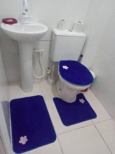 y baño con aseo, lavabo y alfombras azules. en Cantinho da Alegria en Río de Janeiro
