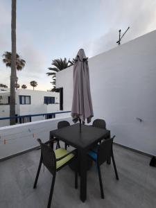 a black table with chairs and an umbrella on a balcony at Waikiki 47 in Corralejo