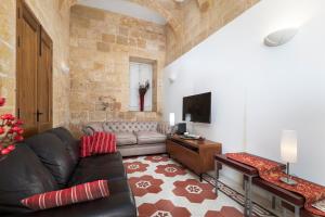 a living room with a leather couch and a television at Traditional & Modern Maltese Townhouse - Rooftop Terrace and Sea Views, close to Birgu Waterfront in Cospicua