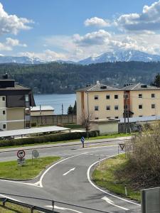 a winding road with buildings and a lake and mountains at Stunning Wörthersee Holiday Home in Sekull