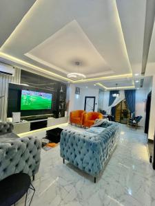 uma sala de estar com um sofá e uma televisão em Morak homes - Smart luxury 4-bed with private swimming pool, PS5, snooker, mini gym in reserved secured estate em Abuja