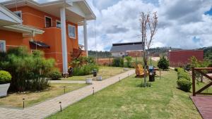 a backyard of a house with a yard with benches at Pousada Caminhos da Vila Chantal in Campos do Jordão