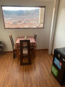 a table and chairs in a room with a large window at Summit Viewpoint House San Blas in Cusco