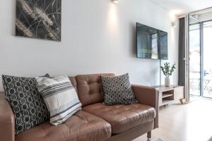 ein Wohnzimmer mit einem braunen Sofa und einem Tisch in der Unterkunft Spirit Apartments - Studio #3 - Balkon - Parkplatz in Engelberg