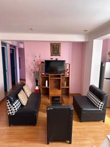 a living room with two black couches and a tv at CASA SANTIAGO in Cusco