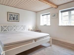 een slaapkamer met een wit bed in een kamer met ramen bij Holiday home Nexø XLIII in Neksø