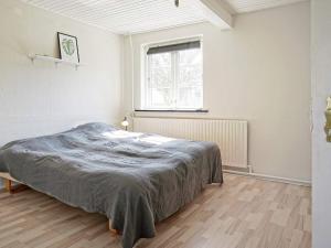 een witte slaapkamer met een bed en een raam bij Holiday home Aakirkeby XLV in Åkirkeby